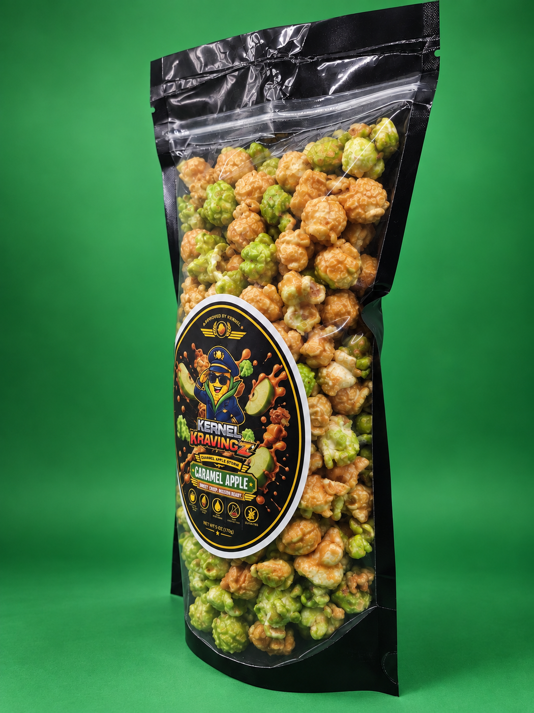 A bag of Keren Kawin's Gourmet Apple Popcorn on a solid green background. The product is packaged in a black resealable stand-up pouch with a clear window showing the green and golden popcorn inside, and a prominent oval label on the front.